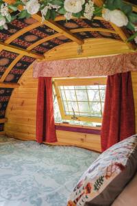 a room with a bed and a window with red curtains at Glamping at The Old Rectory in Dún Ard