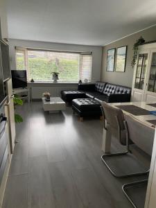 een woonkamer met een bank en een tafel bij Luxe gerenoveerde L-chalet in Putten