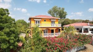 een geel huis met een balkon en bloemen bij Hotel Villa Ordonez in Pochomil