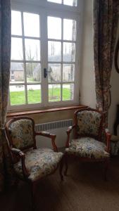 duas cadeiras sentadas em frente a uma janela em Gite du Manoir des Anoteux em Carneville