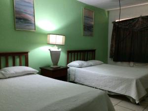 two beds in a room with green walls at Hotel Villa Ordonez in Pochomil