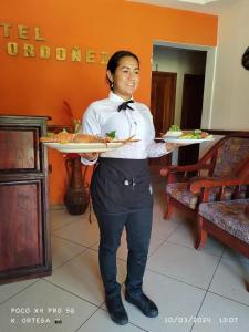 ポチョミにあるHotel Villa Ordonezの女が二皿の食べ物を持っている