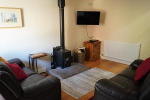 a living room with a couch and a stove at Acorn Cottage, Ashover in Ashover