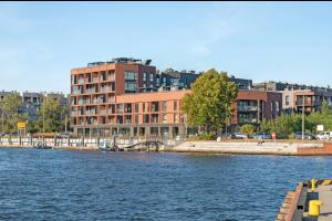 a large building next to a body of water at Welcome Gdańsk Apartaments Nadmotławie Gym and Sauna in Gdańsk