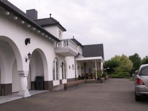 a white house with a car parked in the driveway at Apartment Maasheuvel in Arcen