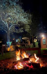 a fire pit with flames in a yard at night at Pousada Boutique das Pedras in Moeda