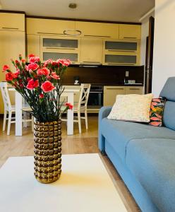 a living room with a blue couch and a vase with red flowers at Namaste in Świnoujście