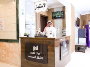 a man standing behind a counter in a restaurant at أبراج العرب للشقق المخدومة Abaraj Alarab Serviced Apartment in Al Madinah
