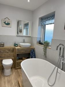 a bathroom with a tub and a toilet and a sink at Church View Anglesey in Trearddur