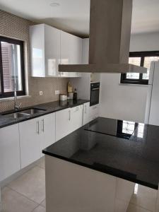 a kitchen with white cabinets and black counter tops at VILLAMOR in Albufeira