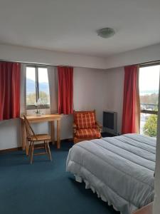 a hotel room with a bed and a desk and windows at TZION B&B in Ushuaia