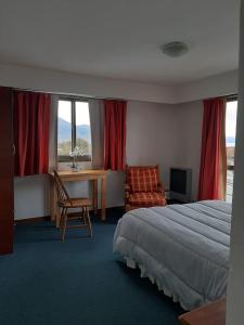 een hotelkamer met een bed, een bureau en een raam bij TZION B&B in Ushuaia