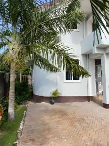 a palm tree in front of a white building at Lema Luxe Villa - Bahari Beach, Dar Es Salam in Dar es Salaam