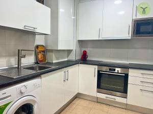 a kitchen with white cabinets and a sink and a washer at Dos Torres Tranvía in Zaragoza