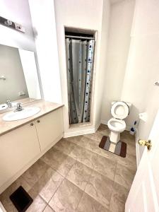 a bathroom with a toilet and a sink and a mirror at Bellhaven Beautiful Home in Brampton