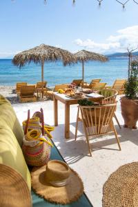 Avlákia的住宿－Aegean Stories pelagos suites，海滩上一张带稻草帽的桌椅