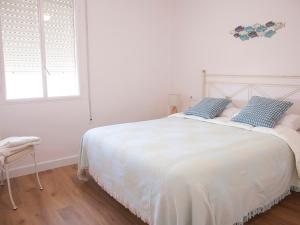 1 dormitorio con 1 cama blanca y 2 almohadas azules en Sanlucarsun Apartamento frente al mar en Sanlúcar de Barrameda