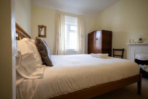 una camera da letto con un letto con lenzuola bianche e una finestra di Oak House in Mid Wales By Seren Short Stays a Machynlleth