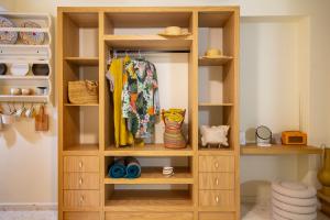 a wooden bookcase in a room with clothes at Aegean Stories pelagos suites in Avlákia +144 photos