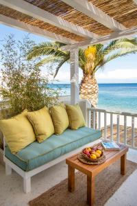 a couch on a porch with a table and the ocean at Aegean Stories pelagos suites in Avlákia