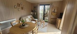 a small living room with a table and a bedroom at "La cabane du sentier", logement original en bois et sur pilotis avec beau jardin et très proche de la mer in Sangatte