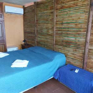 1 dormitorio con cama azul y pared de madera en Posada Mar Azul con Jacuzzi en Punta Del Diablo