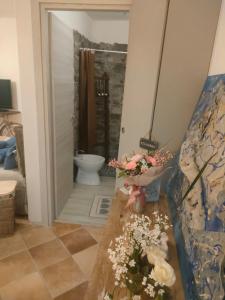 a bathroom with a toilet and flowers on a table at La casa di Noah in Montecatini Terme