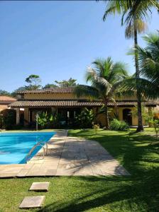 a house with a swimming pool and palm trees at Casa Praia Jardim Acapulco in Guarujá