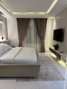 a bedroom with a large bed and a television at Numdor Apartments By The Bond in Port Harcourt