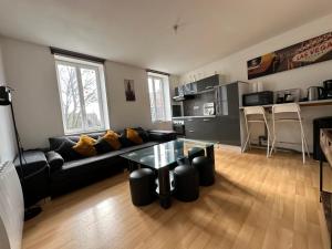 a living room with a black couch and a table at L'Escale des Weppes, appartement 40m2 in Haubourdin