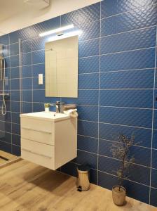 ein Badezimmer mit einem Waschbecken, einem Spiegel und blauen Fliesen in der Unterkunft Apartman Aranyhal City in Sárvár
