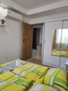 ein Schlafzimmer mit einem Bett mit einer gelben und grünen Decke in der Unterkunft Apartman Aranyhal City in Sárvár