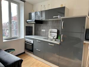 a kitchen with a stainless steel refrigerator and a sink at L'Escale des Weppes, appartement 40m2 in Haubourdin