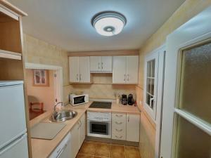 una pequeña cocina con armarios blancos y fregadero en Apartamento Isla Canela Los Cisnes, en Isla Canela