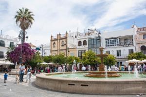 a fountain in a square with people walking around it at Sanlucarsun Apartamento frente al mar in Sanlúcar de Barrameda