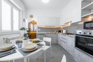 BandeNereSuite Attico في ميلانو: مطبخ أبيض مع طاولة بيضاء وكراسي