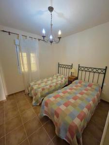 1 dormitorio con 2 camas y lámpara de araña en Apartamento Isla Canela Los Cisnes, en Isla Canela