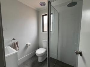 a white bathroom with a toilet and a shower at Denman Van Village in Denman