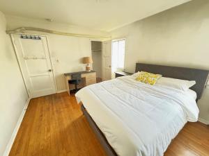 um quarto com uma grande cama branca e uma almofada amarela em Cozy Home in Prime Location em Monterey Park