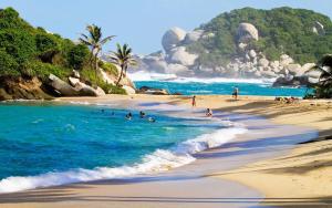 a group of people swimming in the ocean on a beach at Hostal Principio Tayrona in Calabazo