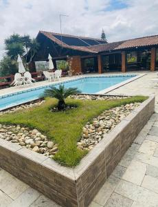 a swimming pool with a retaining wall next to a house at Casa de Campo em Gravatá super aconhegante in Gravatá