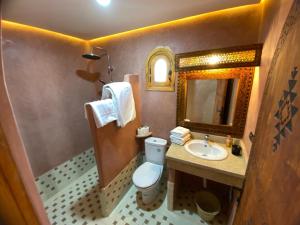 a bathroom with a toilet and a sink and a mirror at riad dar susan in Zagora