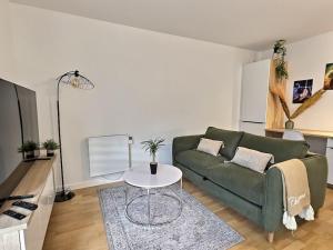 ein Wohnzimmer mit einer grünen Couch und einem Tisch in der Unterkunft Le Bonheur Charmant *Disney*Paris*RER A* in Bussy-Saint-Georges