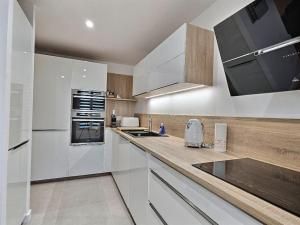 eine Küche mit weißen Schränken und einer Arbeitsplatte in der Unterkunft Le Bonheur Charmant *Disney*Paris*RER A* in Bussy-Saint-Georges