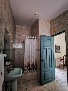 baño con ducha y lavabo y puerta azul en Hotel Bombonaje, en Rioja
