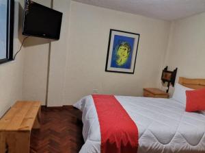 a bedroom with a bed and a flat screen tv at Hostal Monte Carmelo in Baños