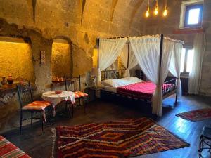 een slaapkamer met een hemelbed en een tafel en stoelen bij Mayaoglu Konagi Hotel in Guzelyurt