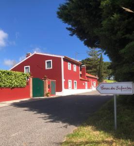 un bâtiment rouge avec un panneau devant lui dans l'établissement Casas Dos Infantes - Turismo Rural, à Caldas da Rainha