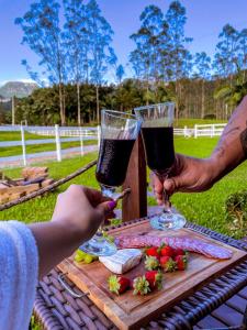 two people are holding wine glasses on a table at Morada do Corujão - Sossego das Águas in Praia Grande
