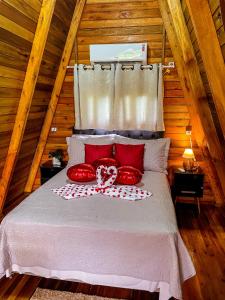a bedroom with a bed with red pillows on it at Morada do Corujão - Encanto in Praia Grande